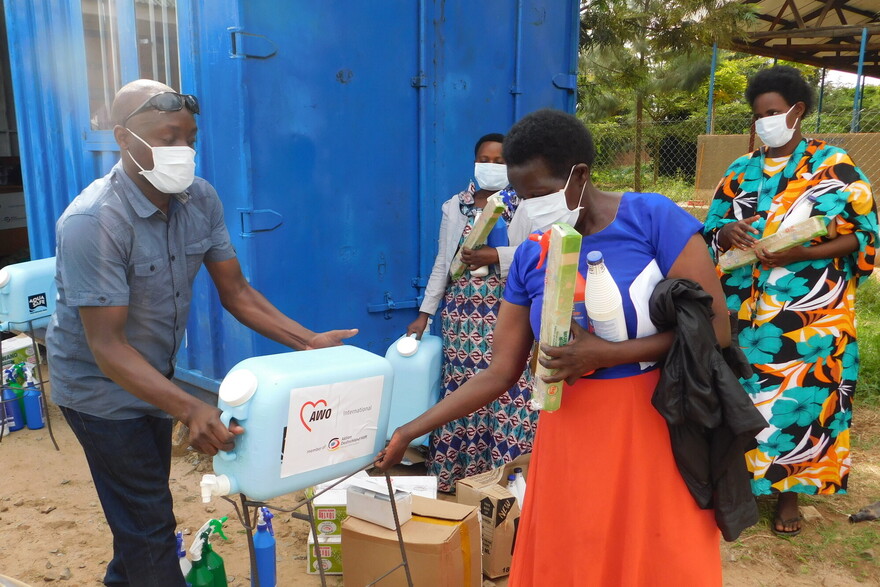 Ein Helfer gibt einer Frau in Uganda einen Kanister mit Trinkwasser Ein Helfer gibt einer Frau in Uganda einen Kanister mit Trinkwasser