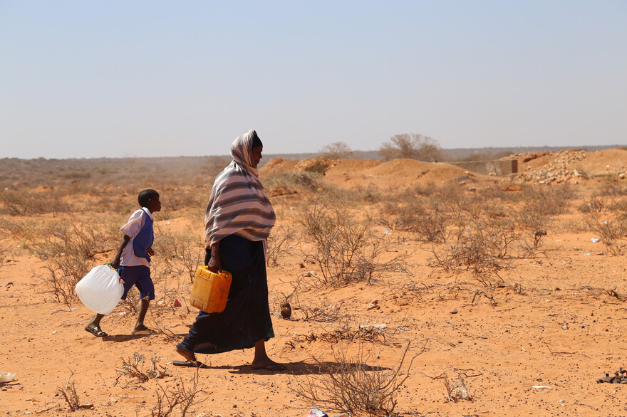 Eine Frau und ein Kind aus Afrika beim Wasserholen in der Wüste Eine Frau und ein Kind aus Afrika beim Wasserholen in der Wüste
